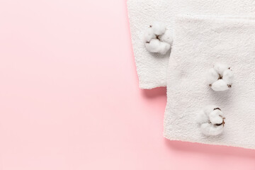 Cotton flowers and soft towels on color background
