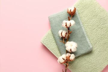 Cotton flowers and soft towels on color background