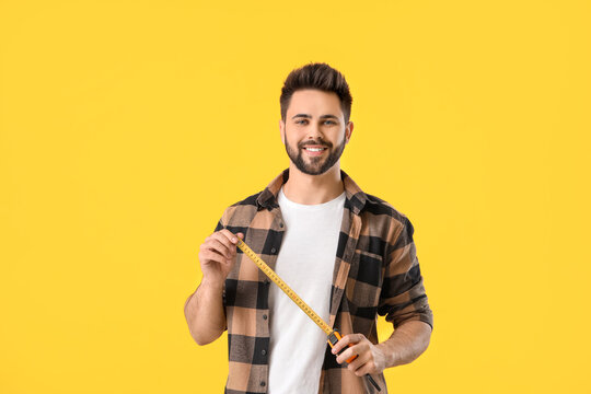 Young man with measuring tape on color background