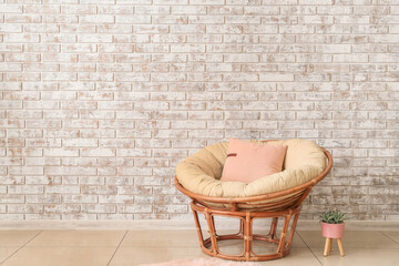 Papasan chair with soft cushion near brick wall in room