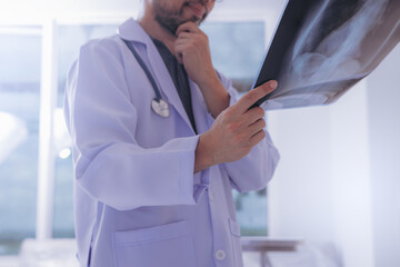 Doctor with examine chest x-ray film for pneumonia of a Covid-19 (Coronavirus) patient at ward hospital.