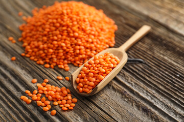 Scoop with red lentils on wooden background
