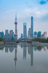 Naklejka premium Sunset view of Waibaidu Bridge and Lujiazui, the skyline and landmark in Shanghai, China, with reflection in front.