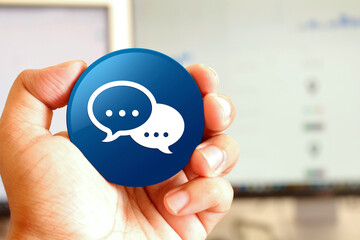 Talk bubble icon blue round button holding by hand infront of workspace background