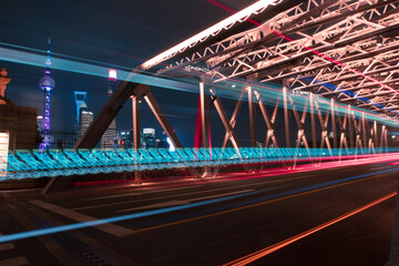 night view of Waibaidu Bridge, a historic landmark in Shanghai, with traffic inside and skyscrapers in then back.