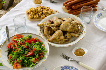 Dinner table with fried chicken wings, tomato salad and snacks