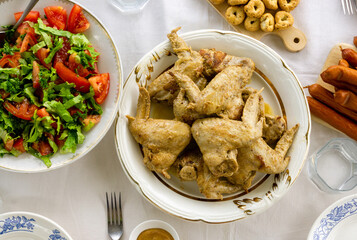 Dinner table with fried chicken wings, tomato salad and snacks