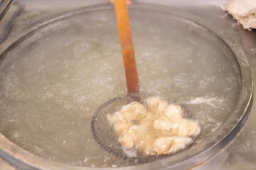 Boiled wonton in a big bowl, traditional cooking process in China.