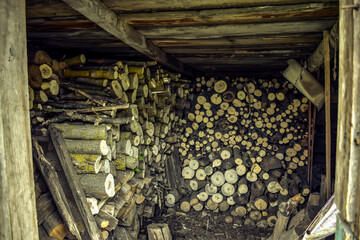 Shed filled with sawn logs of firewood. Preparing for the winter heating season in the countryside. Background with copy space