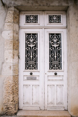 Old white wooden door with ornate windows in European village.