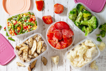 Frozen vegetables. Stocks of food for the winter. Container with frozen vegetables and mushrooms. Top view flat lay background