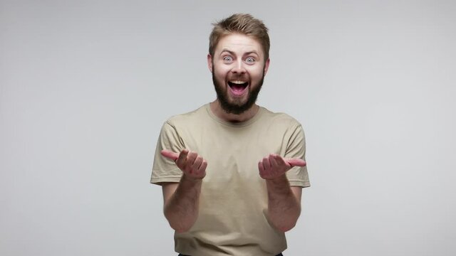 Hey, we need you! Cheerful happy bearded guy smiling laughing carefree and pointing finger to camera, choosing lucky winner, indicating joyous event. indoor studio shot isolated on gray background