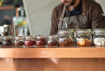 Midsection of barman preparing drinks - herbs and seeds in glass jars
