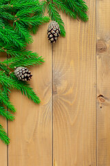 Christmas background with fir branches, cones on a wooden table. space for text.