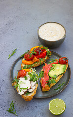 Breakfast or lunch with coffee and different croissant sandwiches with grilled pepper, tomatoes, smoked salmon, turkey, avocado and arugula served with micro green.