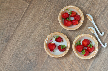 ripe red strawberries in porcelain plates on a wooden brown background