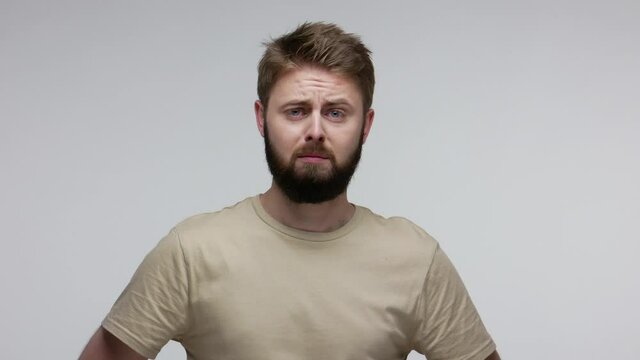 Sad frustrated bearded guy frowning desperately, looking at camera with resentful upset vexed expression, worrying about troubles, feeling depressed negative emotions. studio shot isolated on gray