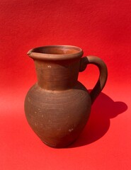 Clay brown vintage jug on a red background