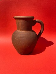 Clay brown vintage jug on a red background