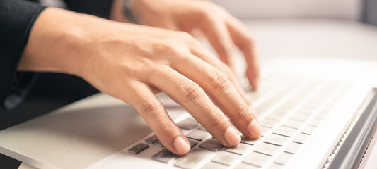 Close up hands of business man using laptop computer working from home, new normal social distancing, work from home concept. Banner portion