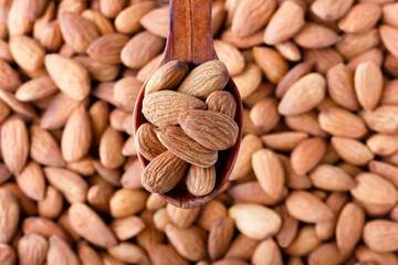 Almonds, a close-up photo. A wooden spoon. The background and texture of a walnut. Image.