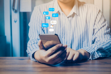 Person using a social media marketing concept on mobile phone with notification icons of like, message, comment and star above smartphone.