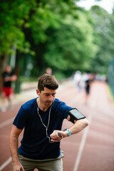 Young man checking his heart rate during work out. Young man exercising on athletics track	