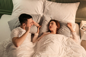Fototapeta na wymiar Young irritated man in bed with snoring wife