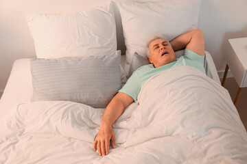 Mature man snoring while sleeping in bed. Apnea problem