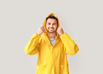Young man in raincoat on light background