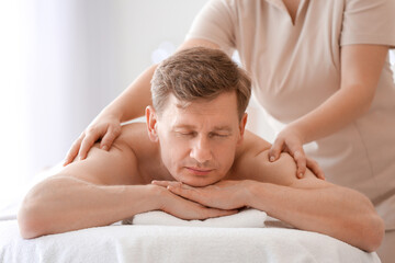Fototapeta na wymiar Handsome man receiving massage in spa salon