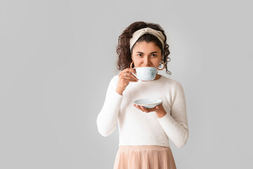 Beautiful young woman with hot tea on grey background