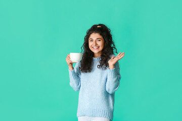Beautiful young woman with hot tea on color background