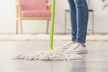 Young woman with mop in flat