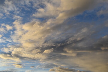 Multi colored photo of clouds at dusk, blue sky with white and gray clouds. 