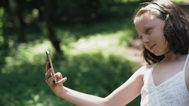 Girl takes a selfie or takes a video on a mobile phone in nature