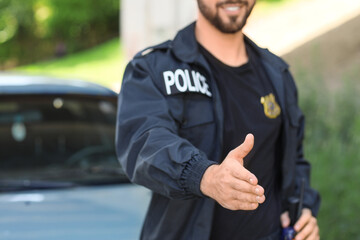 Handsome male police officer giving hand for handshake outdoors