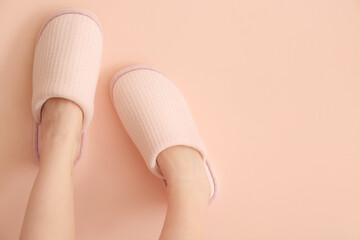 Female legs in soft slippers on color background