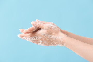 Woman washing hands with soap on color background