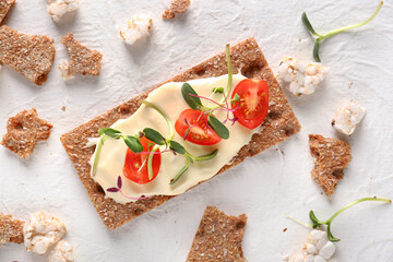 Tasty crispbread with tomato, cheese and sprouts on white background