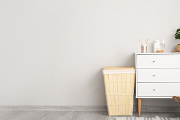 Basket and chest of drawers with cosmetics in bathroom