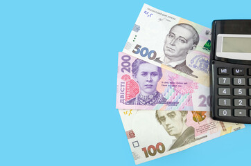 Ukrainian hryvnia and calculator on a blue background. Copy of space. Place for an inscription. View from above