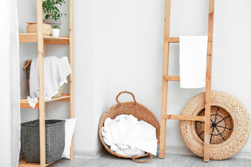 Fototapeta na wymiar Rack and wicker baskets with towels in room