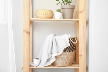 Rack with wicker basket and plaid in room
