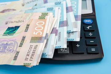 Ukrainian hryvnia and calculator on a blue background. Close-up.