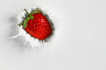 Falling of fresh strawberry into milk