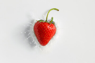 Falling of fresh strawberry into milk