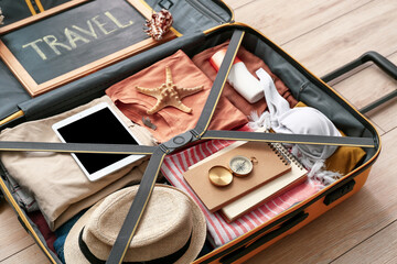 Packed suitcase on wooden background. Travel concept