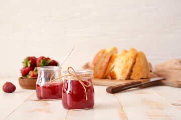 Jars of tasty strawberry jam on white table