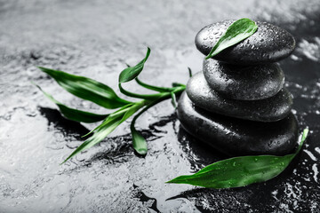 Spa stones and bamboo leaves on dark background